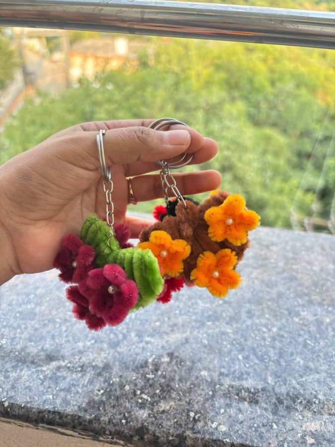Heart Blossom Keychain. Handcrafted heart-shaped keychain made from soft chenille wire, with colorful flowers, pearl centers, and green leaves. Comes in assorted colors. A cute add-on for keys or bags.